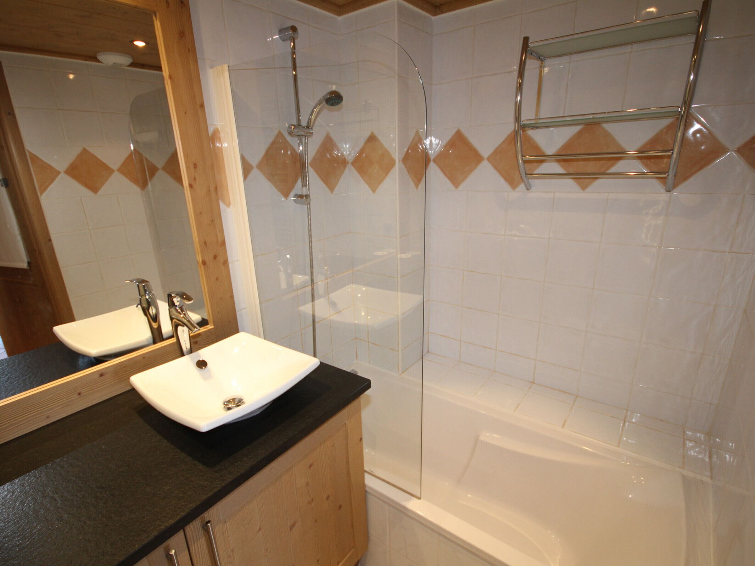 A bathroom with a white sink, two mirrors, a shower with a glass door, and a bathtub.