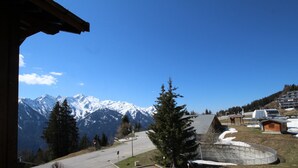 A mountain view with a parking area, a wooden building, and a snow-covered landscape.