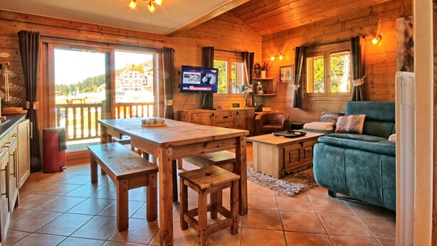 A cozy cabin interior with a wooden interior, a dining area, a sofa, and a TV.