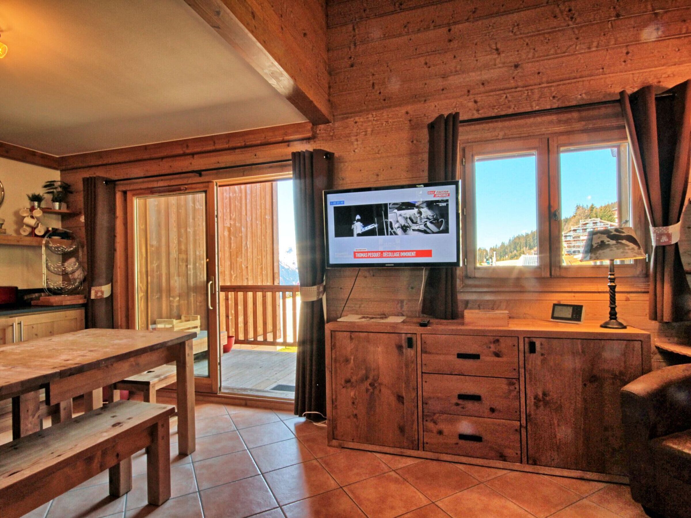 Un intérieur en bois avec un téléviseur fixé au mur, une table en bois et un banc.