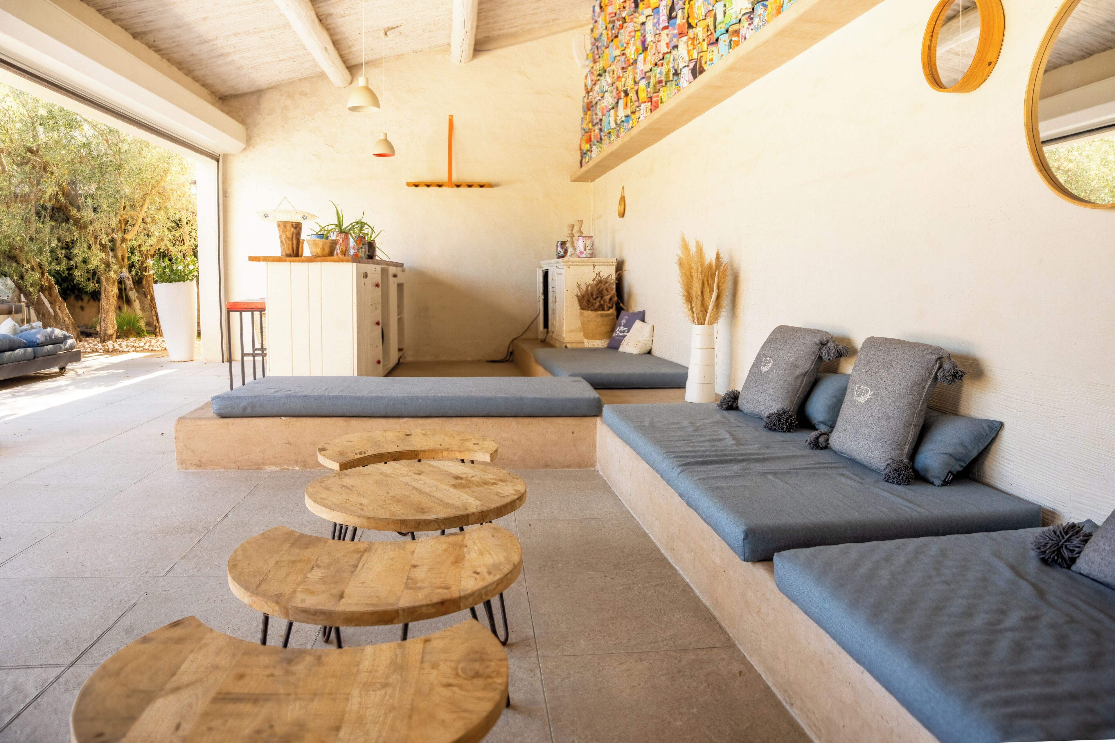 Un interno moderno con un divano componibile, tavolini in legno rotondi e una mensola decorativa a parete.