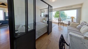 Camera da letto moderna con parete divisoria in vetro, una poltrona, una sedia e vista sull'esterno.