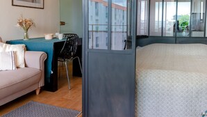 Una camera moderna con un letto, una scrivania, una sedia, un divano e una finestra vista edifici.