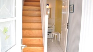 A wooden staircase leading to a room with a white door, a small table, and a radiator. - Charming Breton House Steps from Saint-Guirec Beach, Ploumanac’h – 2 Beds, Garden, Pet-Friendly (Perros-Guirec)