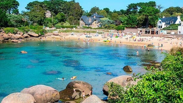 A coastal beach with clear water, large rocks, and houses in the background. - Charming Breton House Steps from Saint-Guirec Beach, Ploumanac’h – 2 Beds, Garden, Pet-Friendly (Perros-Guirec)