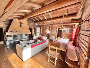 L’intérieur d’un chalet rustique, avec une cheminée en pierre, des meubles en bois et un coin repas.
