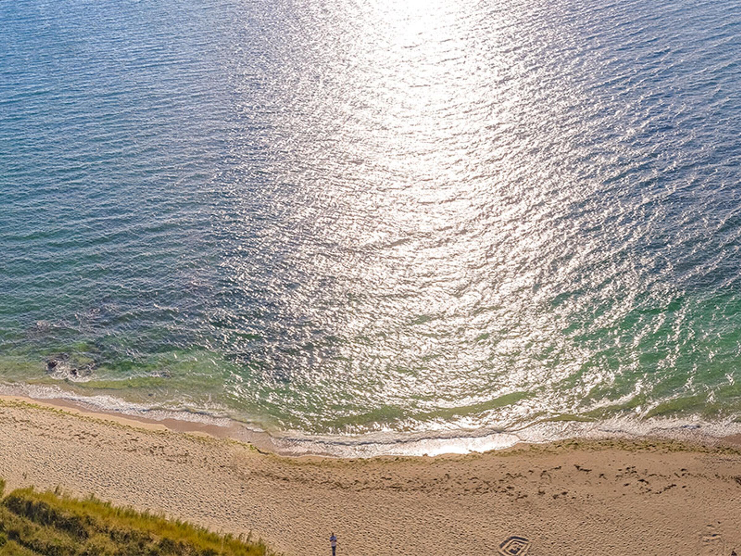 Uma praia com vista clara do oceano e uma faixa de areia.
