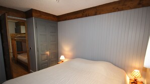 A bedroom with a large bed, wooden headboard, two bedside lamps, and a door leading to another room. - Les Saisies - 2-room with fireplace for 6 people (Les Saisies)