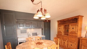 A kitchen with wooden cabinets, a dining table with chairs, and a chandelier. - Les Saisies - 2-room with fireplace for 6 people (Les Saisies)