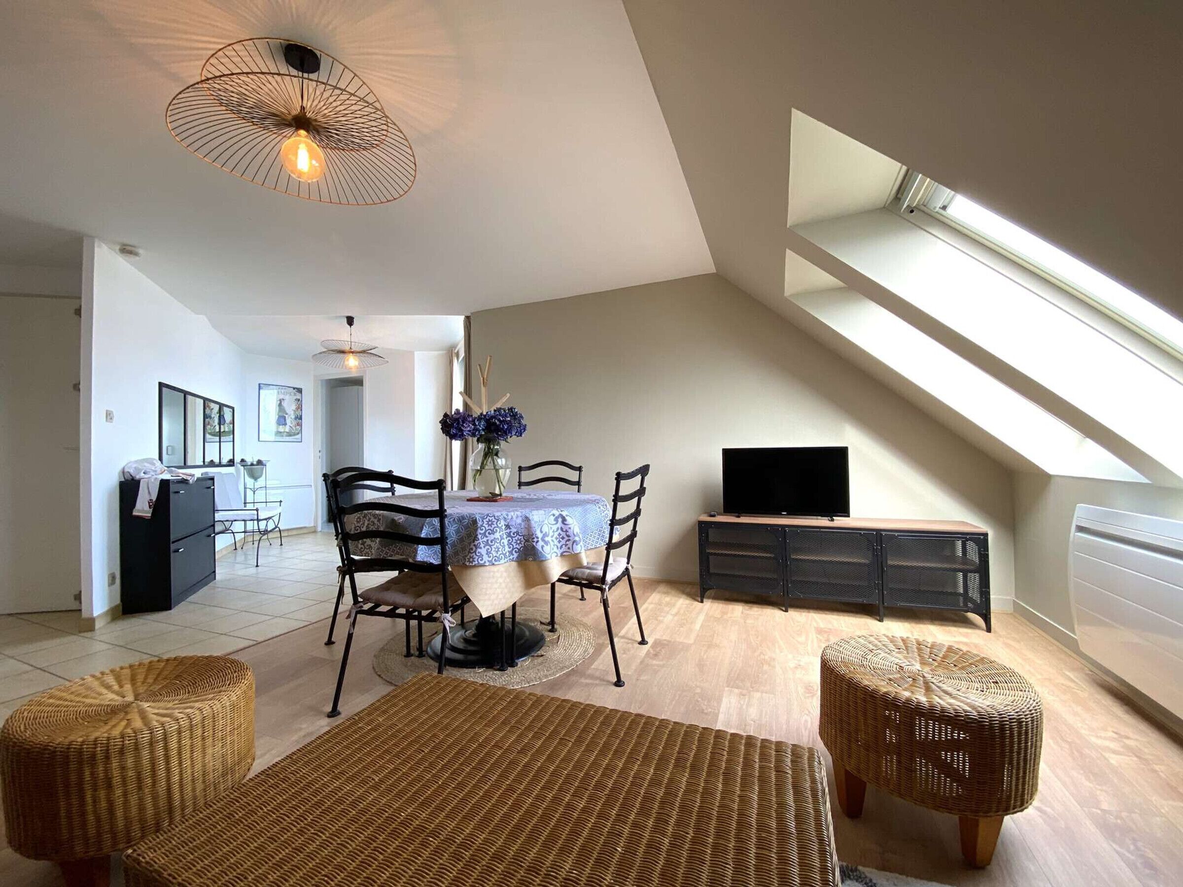 A dining area with a table, chairs, and a television on a stand.