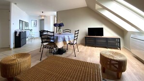 Un comedor con una mesa, sillas y un televisor sobre un mueble.