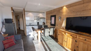 A modern living room with a grey sofa, wooden cabinets, and a flat-screen TV. - Renovated 2-room with parking and wifi, pets allowed - Les Saisies (Les Saisies)