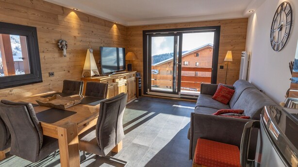 A modern living room with a wooden interior, a dining area, a sofa, a television, and a view of the outside. - Renovated 2-room with parking and wifi, pets allowed - Les Saisies (Les Saisies)