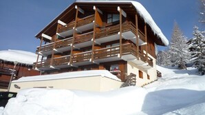 A multi-story wooden chalet with balconies, surrounded by snow-covered trees. - Renovated 2-room with parking and wifi, pets allowed - Les Saisies (Les Saisies)