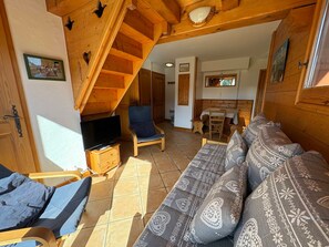 Een houten interieur met een bank, een televisie en een stoel.