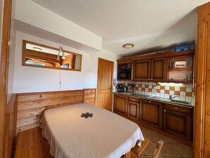 Een kleine keuken met houten kastjes, een magnetron en een spoelbak.
