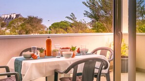 Un área de comedor al aire libre con una mesa lista para dos personas, sillas y distintos utensilios de mesa.