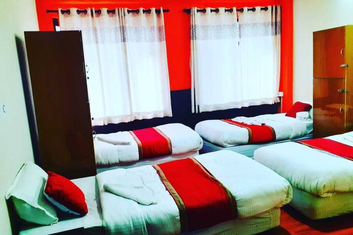 A hotel room with two beds, each with red and white bedding, and a wardrobe.