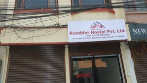 Un edificio de varios pisos con un letrero que dice Rambler Hostel Pvt. Ltd. y un restaurante.