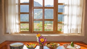 Una mesa de comedor con tres platos de comida y un florero junto a una ventana con vista a la montaña.