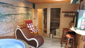 A cozy room with a hot tub, a reclining chair, and a bar area with stools.
