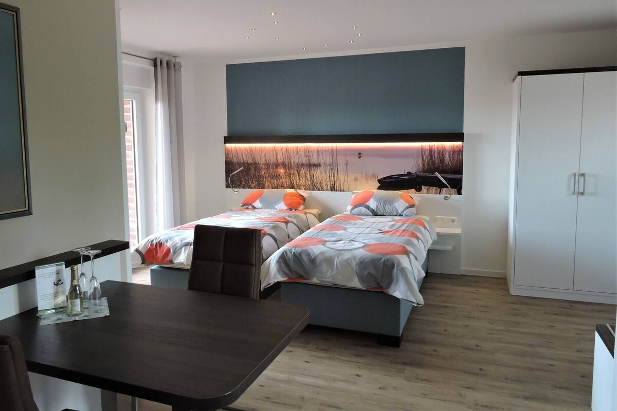 A hotel room with two beds, a desk, and a wardrobe.