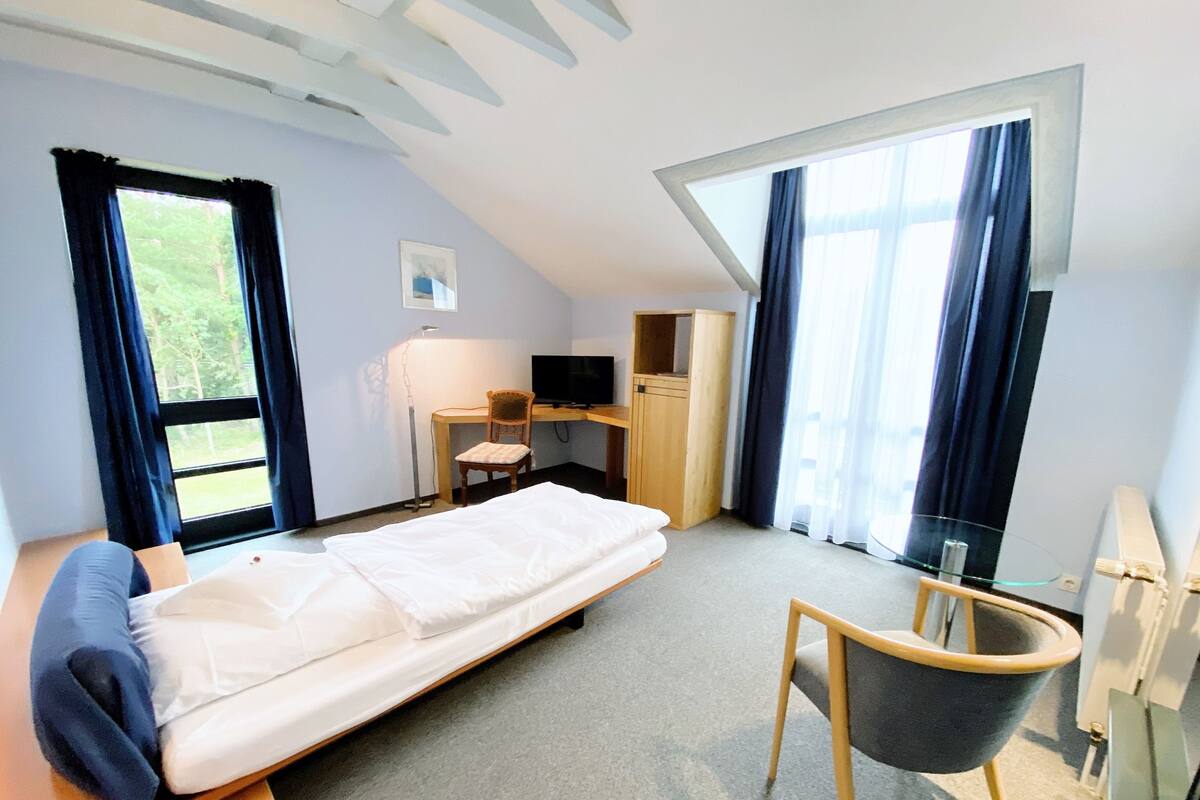 A bedroom with a bed, a desk, a chair, a TV, and a wardrobe.