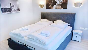 Ein modernes Hotelzimmer mit einem großen Bett, zwei Nachttischen, einer Wandleuchte und einem Bilderrahmen mit einem Reh-Motiv.