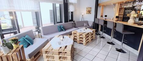 Un salon moderne avec un canapé, une table basse et un coin bar équipé de tabourets.