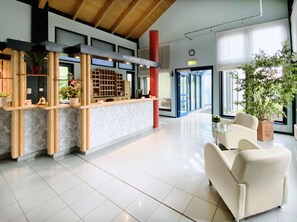 Un área de recepción con mostrador, zona de estar y ventanas amplias.
