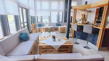 Un interior moderno con un sofá, mesas de madera y una zona de bar.