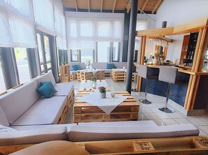 Ein modernes Interieur mit einer Couch, Holztischen und einer Bar.