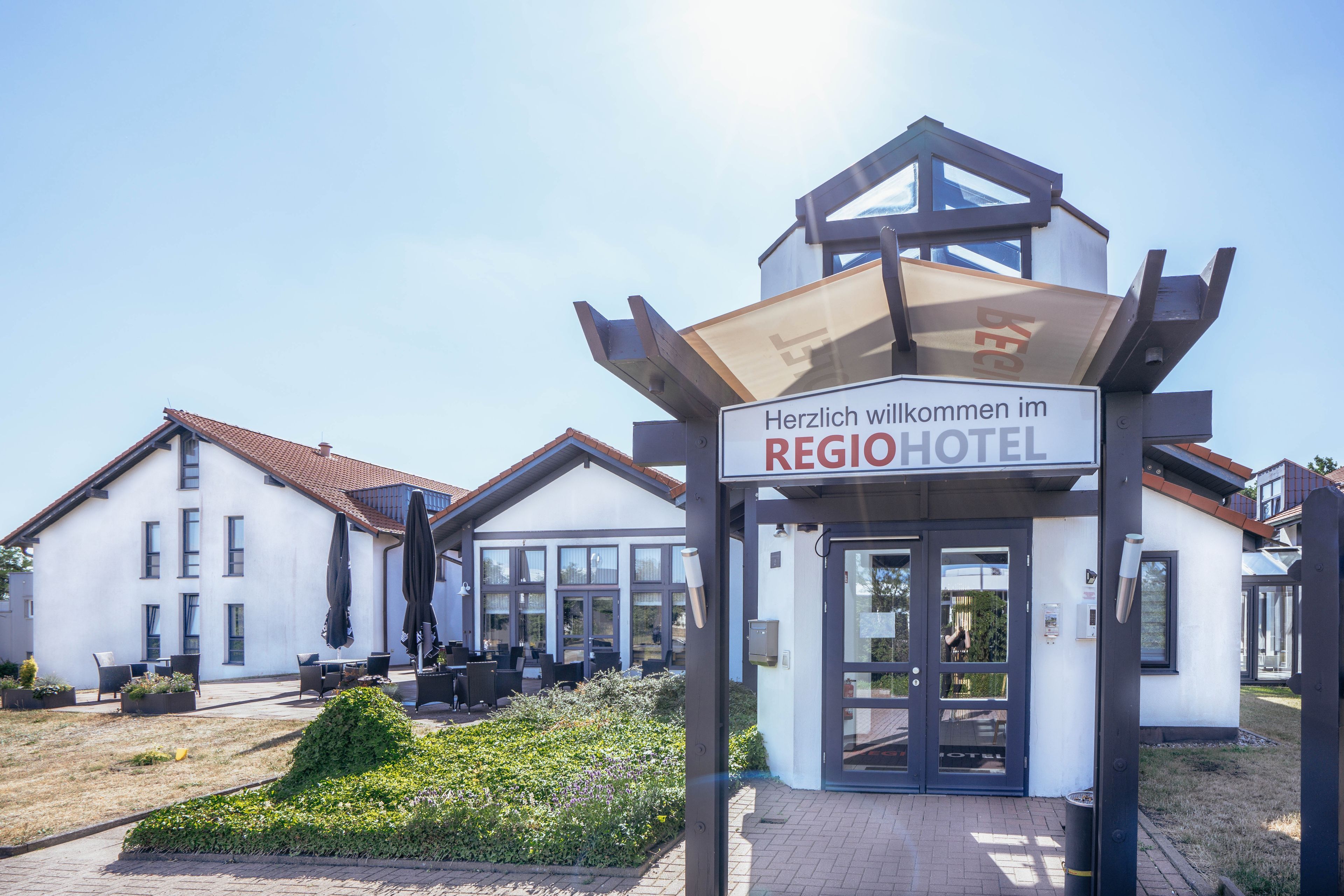 Ein Hotel Eingang mit einem Schild, auf dem 'Herzlich willkommen im REGIOHOTEL' steht.