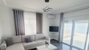 A modern living room with a sectional sofa, a coffee table, and a flat-screen TV. - Makla Apartaments (Sarandë)