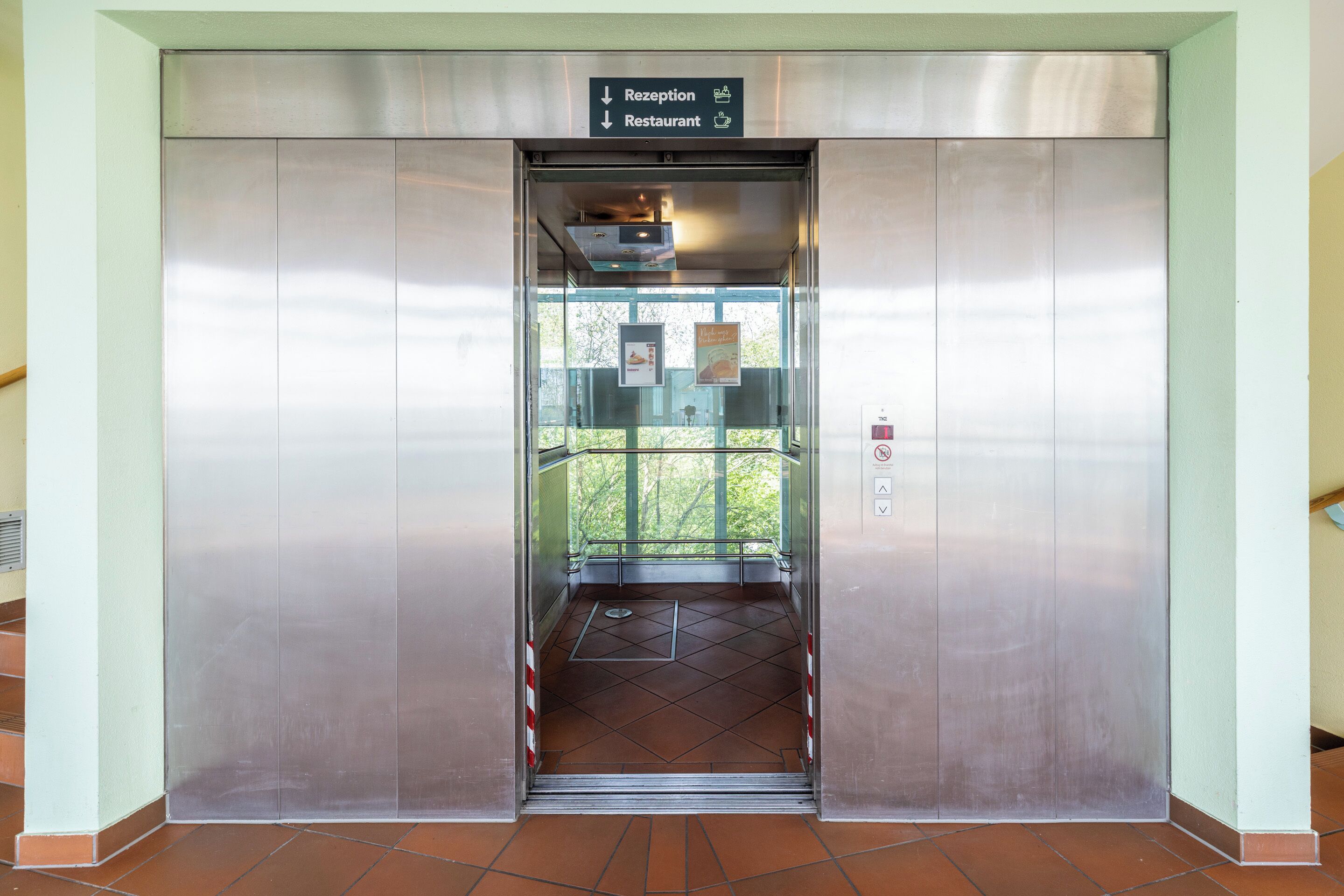 An elevator with a sign indicating directions to the reception and restaurant.