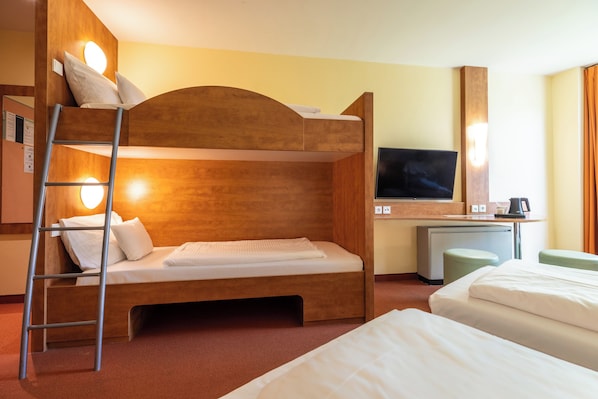 Una habitación de hotel con una cama litera, un escritorio con una computadora, un televisor y una escalera.