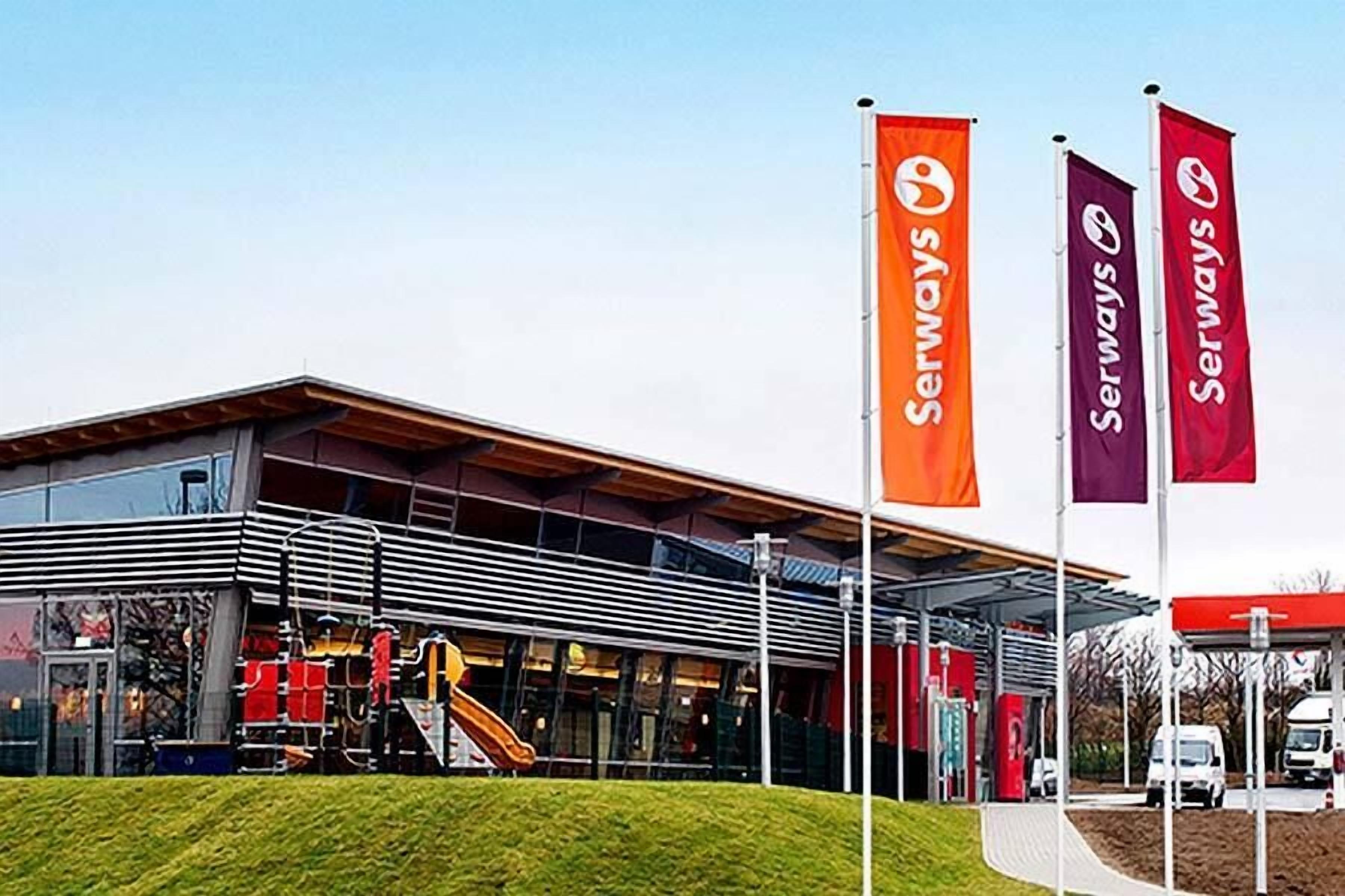 A modern building with a glass facade, a covered entrance, and a playground area.