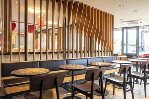 A restaurant interior with booths, round tables, and a wooden partition. - Raststättenhotel Holledau (Schweitenkirchen)