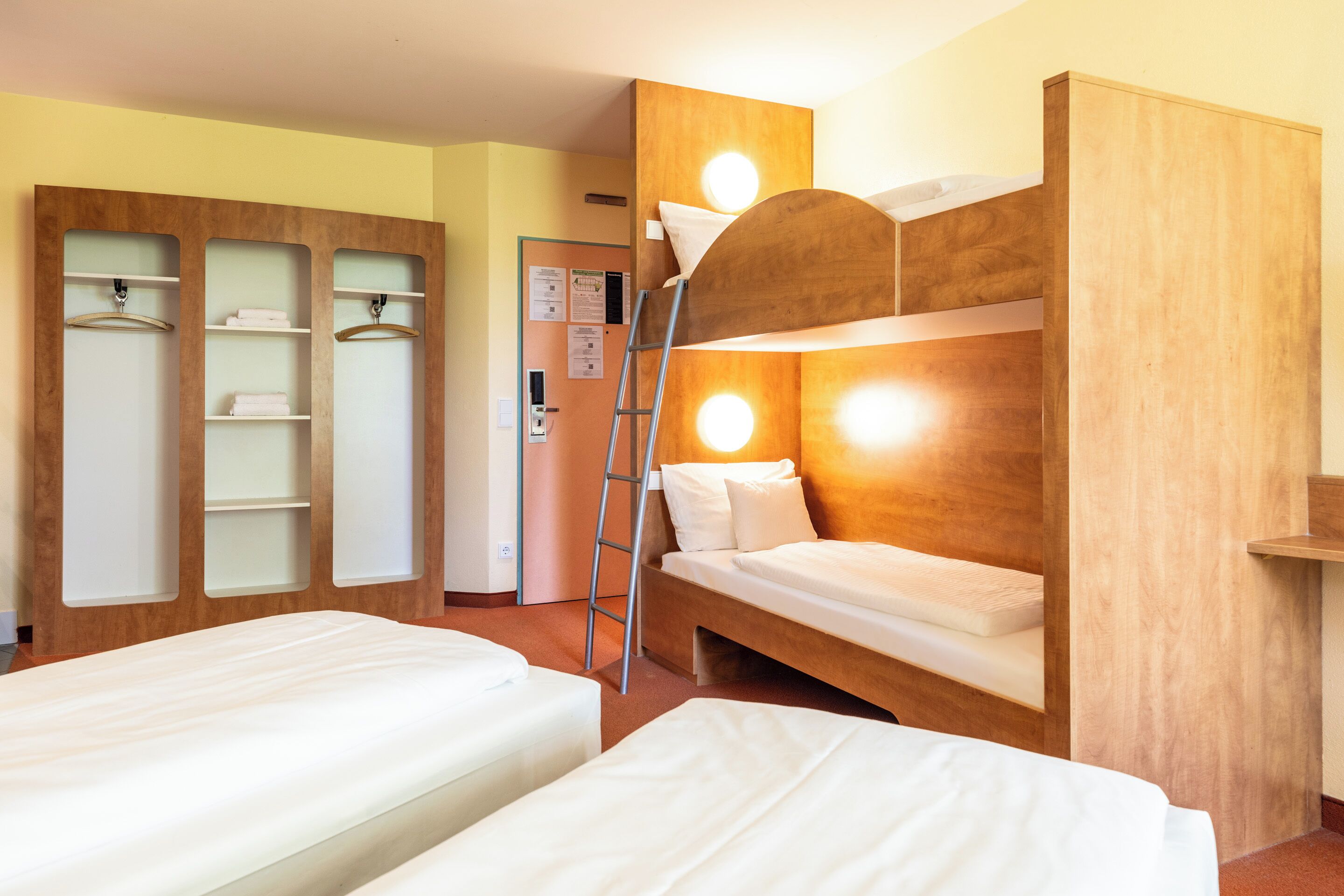 A room with bunk beds, a wardrobe with shelves, and a ladder.