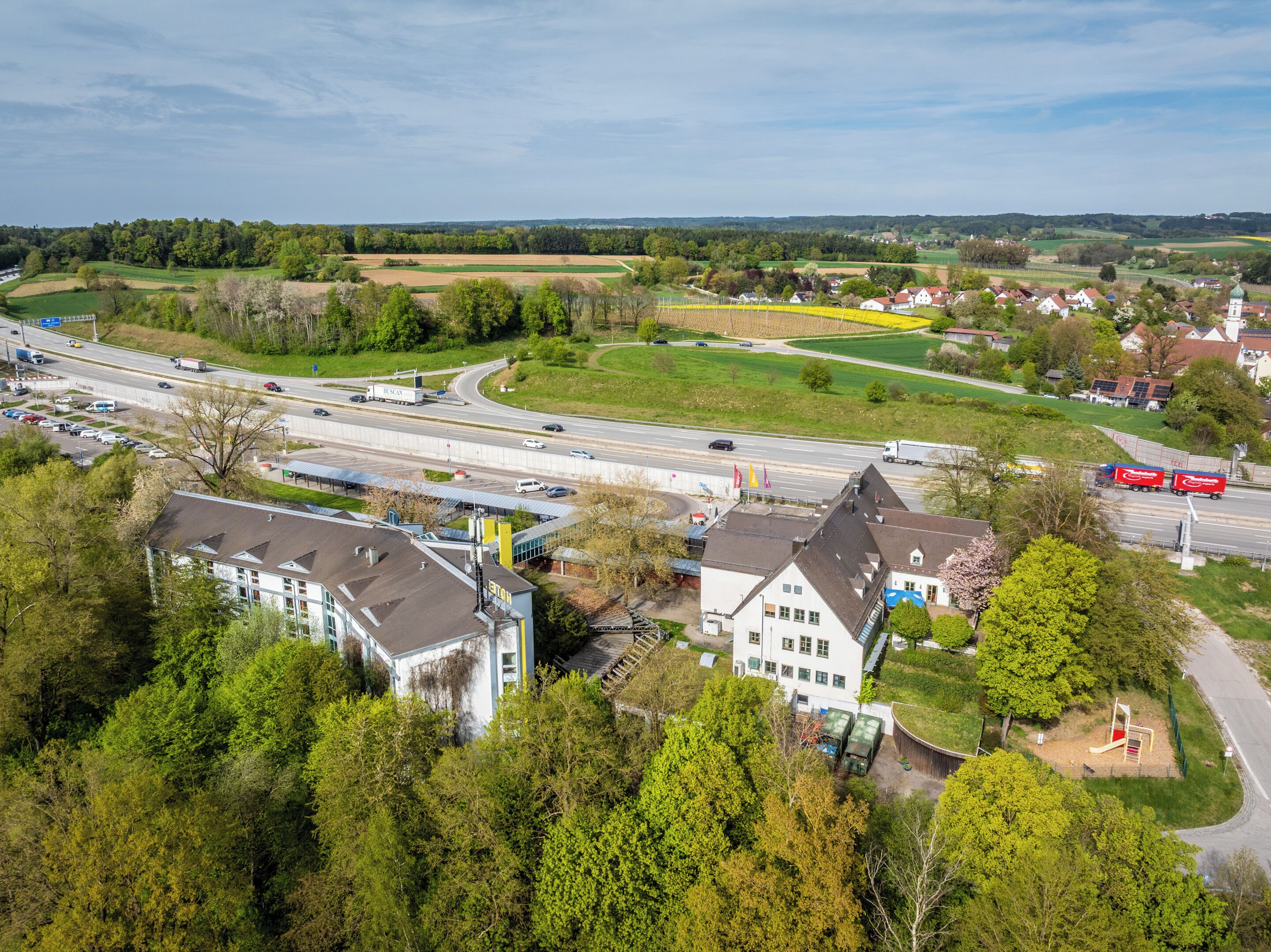 An aerial view of a town with a highway, buildings, and greenery.