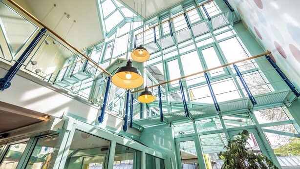 Un interior modern amb grans finestres, un sostre de vidre i lluminàries penjants.