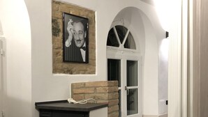 Un pasillo con una fotografía blanco y negro, un muro decorativo de ladrillo y una puerta blanca con paneles de vidrio.