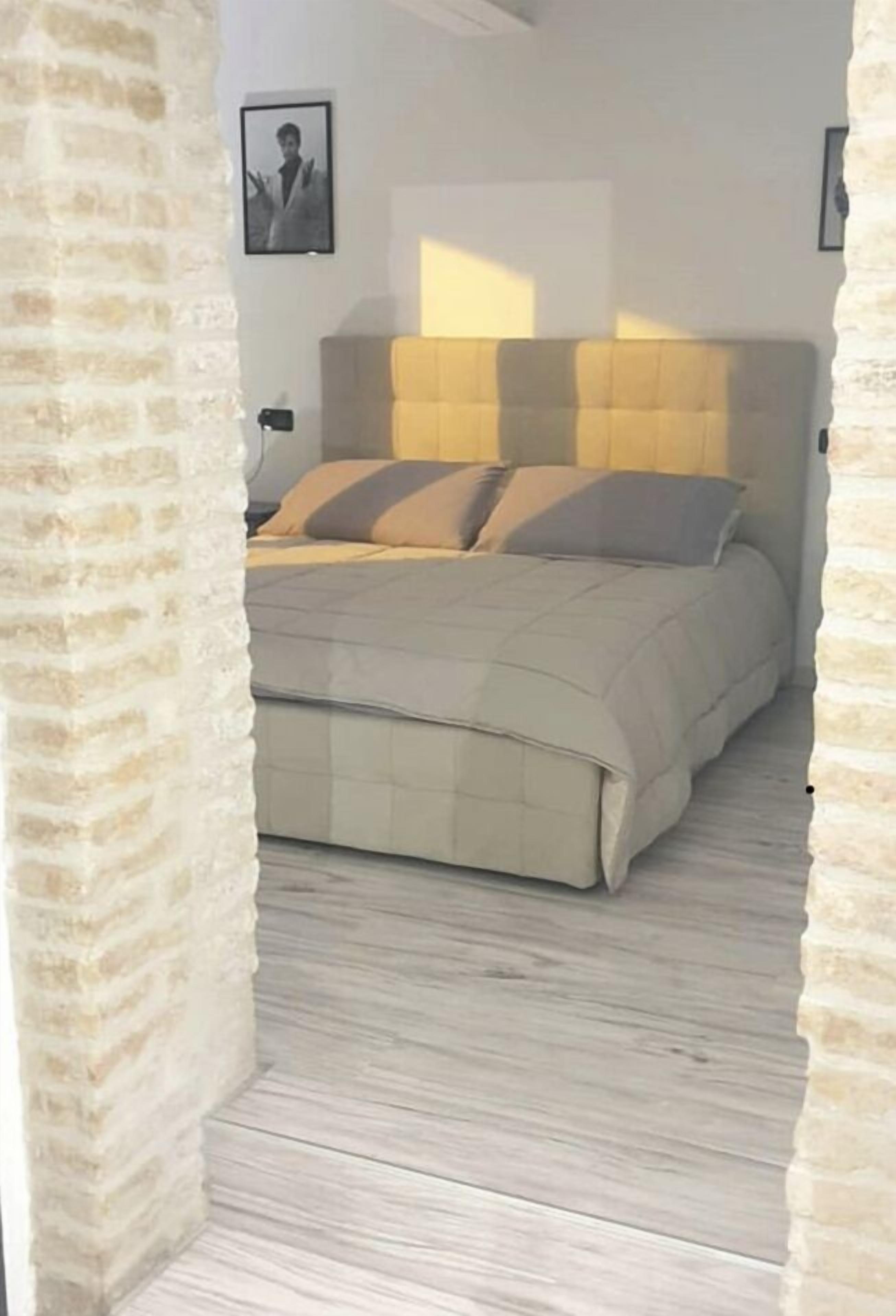 Une chambre à coucher avec un lit, une tête de lit et un plancher en bois.