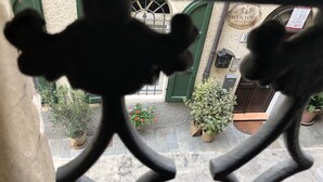 Vista a través de una reja metálica, con un edificio al fondo y un letrero que dice "MENUTORE ROOM & BREAKFAST".