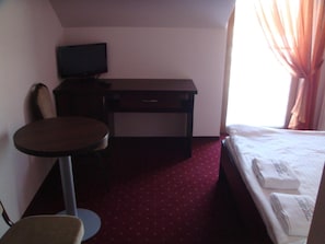 A hotel room with a bed, a desk, a chair, and a television. - Gosciniec Europejski (Miedziana Góra)