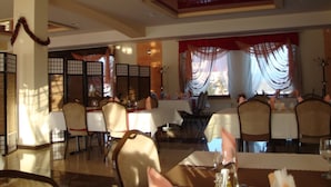A dining area with tables and chairs, a decorative partition, and a view through the window. - Gosciniec Europejski (Miedziana Góra)