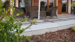 An outdoor seating area with wicker furniture and a white umbrella. - Gosciniec Europejski (Miedziana Góra)