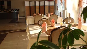 A dining area with tables set for two, chairs, and a decorative partition. - Gosciniec Europejski (Miedziana Góra)