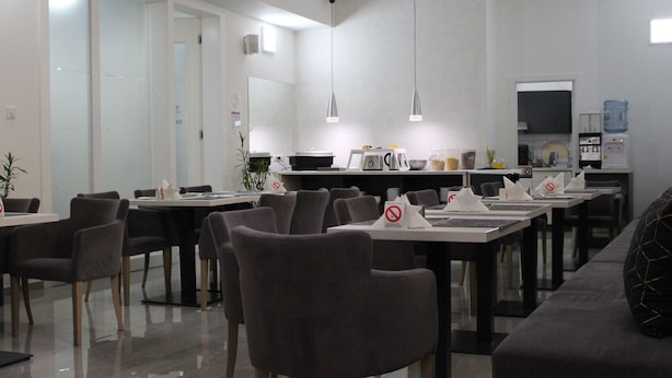 A modern dining area with tables and chairs, a water dispenser, and a coffee machine. - Garni Hotel 11Tica DM (Novi Sad)