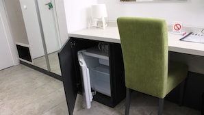 A workspace with a desk, a green chair, a white lamp, and a closed door. - Garni Hotel 11Tica DM (Novi Sad)
